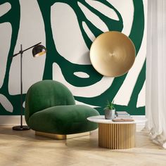 a green chair sitting next to a table in front of a wall with an abstract design on it