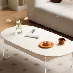 a coffee table with flowers and a book on it in front of a white couch