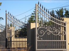 an iron gate with decorative designs on the top and bottom, in front of a house