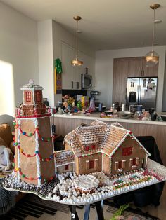 two gingerbread houses are on a table in front of a kitchen with an island