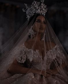 a woman in a wedding dress with a veil on her head and wearing a tiara