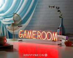 a neon sign sitting on top of a table next to a vase with flowers in it