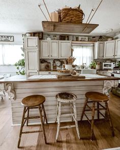 an old fashioned kitchen with stools in front of the island and two baskets hanging above it