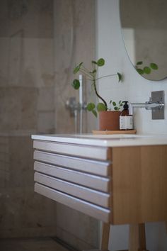 a bathroom with a sink, mirror and potted plant on the counter in front of it