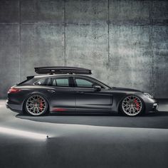 a car with a surfboard on top of it's roof rack in front of a concrete wall