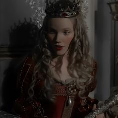 a woman in a red dress with a crown on her head and long curly hair