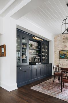 a dining room table and chairs in front of a large china cabinet with glass doors