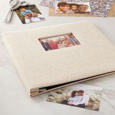 an open photo album sitting on top of a table next to two pictures and scissors