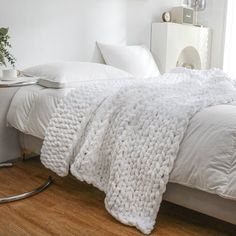 a bed with white blankets and pillows on top of it