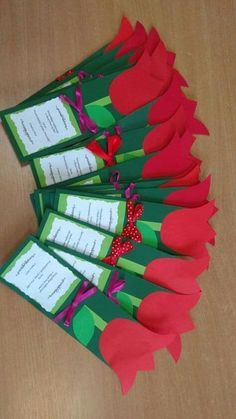 five red roses are on top of green paper with notes attached to them, sitting on a wooden table