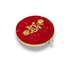 a red and gold box with flowers on the lid is sitting on a white surface