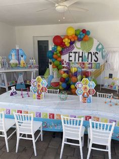 a table set up for a birthday party with balloons and decorations on the wall behind it