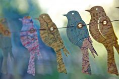 some little birds are hanging from a clothes line with map paper on it's strings