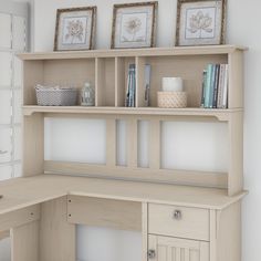 a white desk with some books on top of it and pictures above the desk in front of it