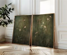 two paintings are sitting on the floor next to a potted plant in an empty room