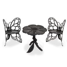 three metal butterflies sitting on top of each other next to a small table and chairs