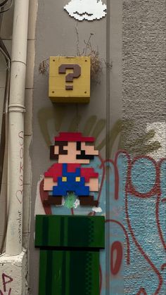 a nintendo game character on the side of a building with graffiti and a question sign above it