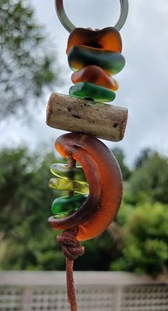 a wind chime hanging from a tree branch with colorful glass beads on it's end