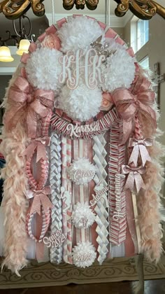 a pink and white decorated chair with feathers on the back, monogrammed in silver