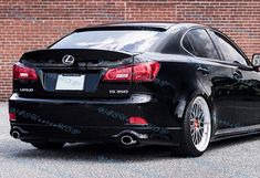 a black car parked in front of a brick wall