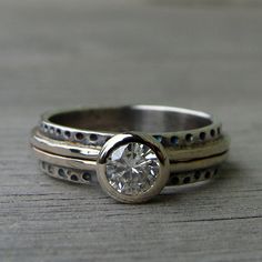 two silver rings sitting on top of each other with a diamond in the middle and dots around them