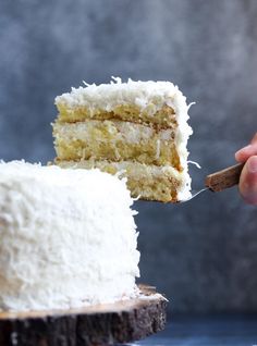 someone is holding a fork with a piece of coconut cake on it and the rest of the cake has been cut