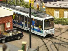 a train traveling down tracks next to a street filled with cars and people on it