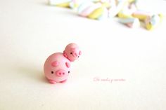 two small pink pig figurines sitting next to each other on a white surface