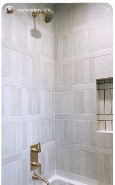 a bathroom with white tile and gold faucet in the bathtub next to a window