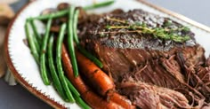 pot roast with carrots, green beans and beef on a white plate that says slow cooker sunday