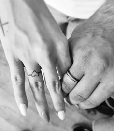 two people holding hands with tattoos on their fingers and one is holding the other's hand