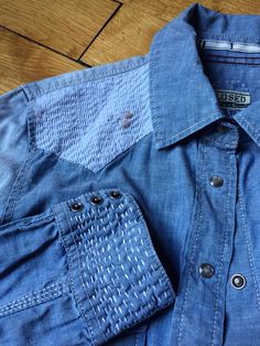 a denim shirt with holes and buttons on the chest