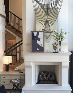 a white fireplace in a living room next to a stair case with pictures on it