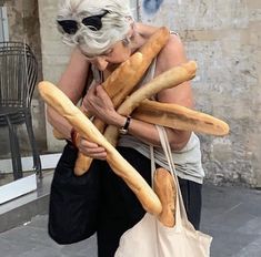 an older woman carrying breadsticks in her arms