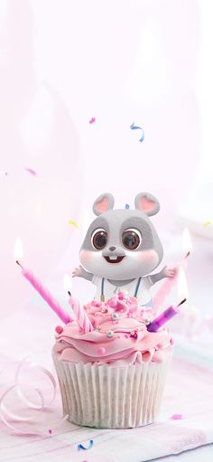 a cupcake with pink frosting and lit candles in the shape of a mouse