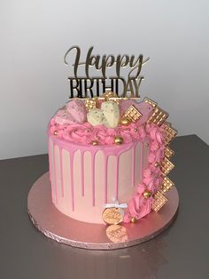 a birthday cake with pink frosting and gold decorations