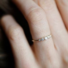 a woman's hand wearing a gold ring with three small diamonds on the side