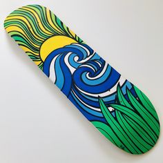 a skateboard painted with an image of waves and sun on the bottom half of it