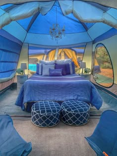 the inside of a tent with blue bedspreads and pillows on top of it