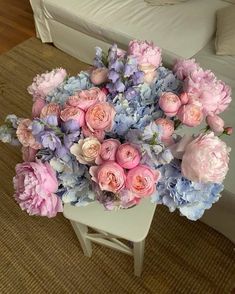 a bouquet of pink and blue flowers sitting on top of a white table next to a couch