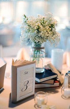 a table topped with books and vases filled with white baby's breath flowers