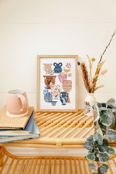 a wooden table topped with vases and plants next to a framed art print on top of a bamboo shelf