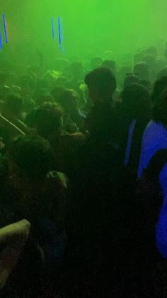 a group of people standing in front of a green light at a concert or party