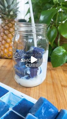 a mason jar filled with blue jello next to a pineapple and ice cubes