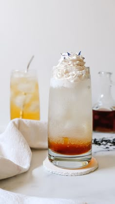 two glasses filled with drinks sitting on top of a table next to white towels and napkins