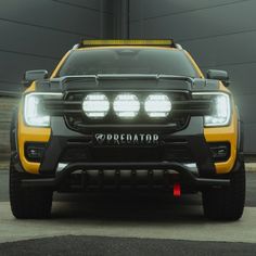 the front end of a yellow truck with lights on it's headlamps