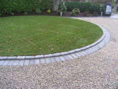 a circular lawn area with brick edgings and grass in the middle, surrounded by gravel