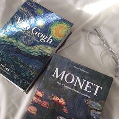 two books sitting on top of a bed next to each other near eyeglasses