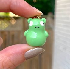 a person holding a tiny green frog keychain