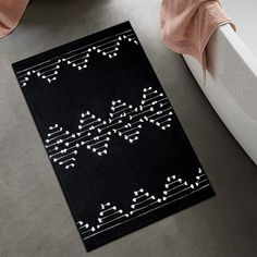 a bath tub sitting next to a black and white rug on top of a floor